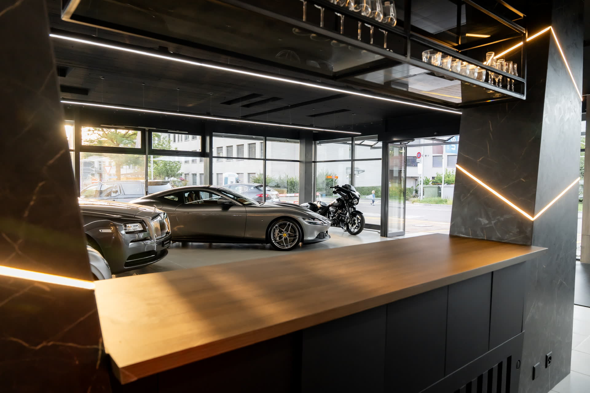 Holztresen mit Lichtlinien, dahinter Bentley und Rolls-Royce